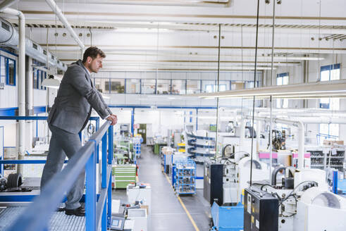 Geschäftsmann im Obergeschoss mit Blick auf die Fabrik - DIGF11115