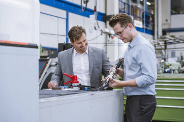 Two businessmen examining a product in a factory - DIGF11127