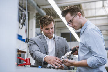 Zwei Geschäftsleute begutachten ein Produkt in einer Fabrik - DIGF11129