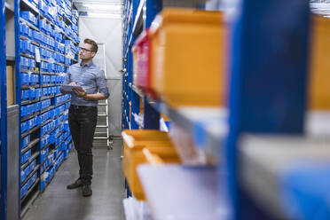 Man using tablet in storehouse of a factory - DIGF11136