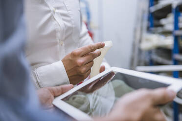 Nahaufnahme von zwei Geschäftsleuten mit Tablet und Produkt in einer Fabrik - DIGF11148