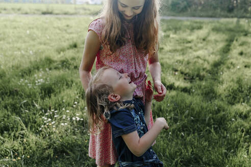 Glückliches Mädchen mit ihrer kleinen Schwester auf einer Wiese - OGF00422