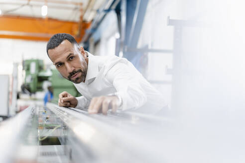 Geschäftsmann prüft Metallstange in Fabrikhalle - DIGF11168