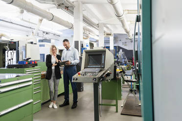 Businessman and woman using tablet in factory hall - DIGF11176