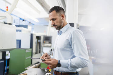 Geschäftsmann mit Tablet in einer Fabrikhalle - DIGF11184