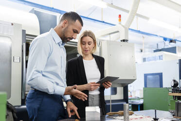 Businessman and woman with tablet and workpiece in factory hall - DIGF11189