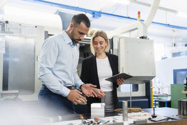 Geschäftsmann und Frau mit Tablet und Werkstück in einer Fabrikhalle - DIGF11190