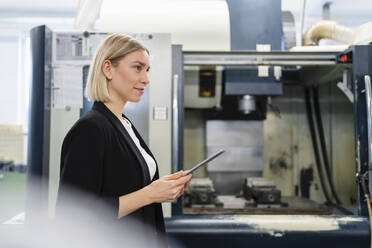 Lächelnde Frau mit Tablet in einer Fabrikhalle - DIGF11191