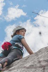 Junge Frau klettert auf Felsen gegen den Himmel - FVSF00293