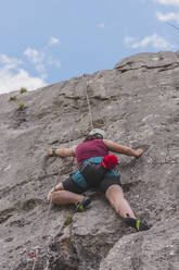 Young woman rock climbing against sky - FVSF00303