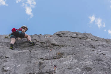 Junge Frau klettert auf einen Felsen und blickt in den Himmel - FVSF00304