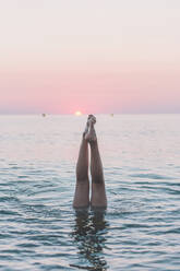 Teenager-Mädchen macht Handstand im Meer bei Sonnenaufgang - FVSF00315