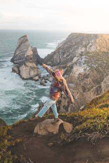 Junge Frau balanciert auf einem Felsen am Strand von Ursa, Region Lisboa, Portugal - FVSF00340