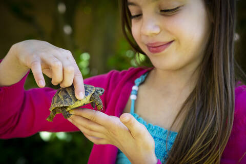 Lächelnde Mädchenhände halten kleine Schildkröte, lizenzfreies Stockfoto