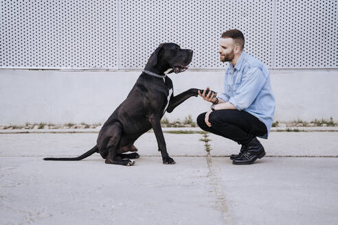 Junger Mann unterrichtet seinen Hund im Freien - EBBF00117