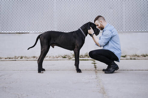 Junger Mann Kopf an Kopf mit seinem Hund im Freien - EBBF00118