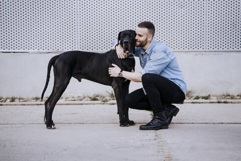 Glücklicher junger Mann, der seinen Hund im Freien knuddelt, lizenzfreies Stockfoto