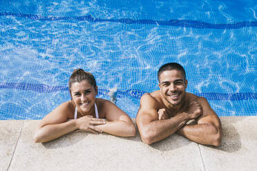 Lächelndes junges Paar im Schwimmbad stehend - ABZF03135