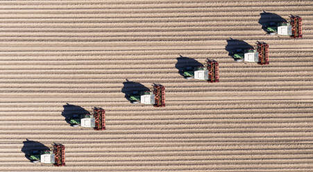 Deutschland, Hessen, Bergstarsse, Luftaufnahme von Traktoren beim Pflügen eines braunen Feldes im Frühling - AMF08113