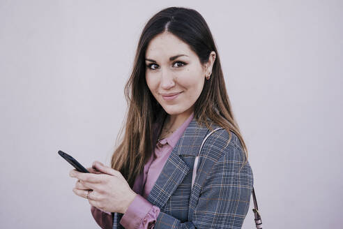 Porträt einer lächelnden Frau mit Smartphone - EBBF00137