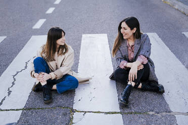 Zwei Frauen sitzen zusammen auf einem Zebrastreifen - EBBF00155