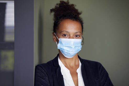 Portrait of businesswoman wearing light blue protective mask - RBF07686