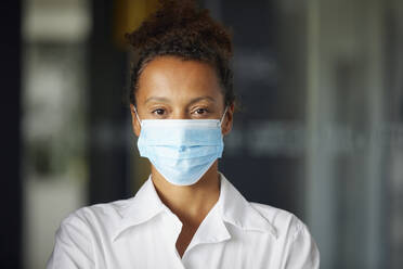 Portrait of businesswoman wearing light blue protective mask - RBF07689