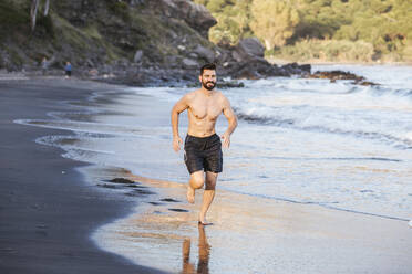 Handsome shirtless mid adult man running at beach during sunset - LJF01519