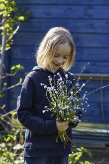 Porträt eines Mädchens im Kleingarten mit einem Blumenstrauß - MCF00823