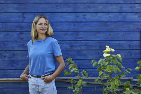 Porträt einer Frau vor einem blauen Gartenhäuschen - MCF00831