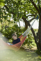 Girl in hammock reading a book - MCF00835