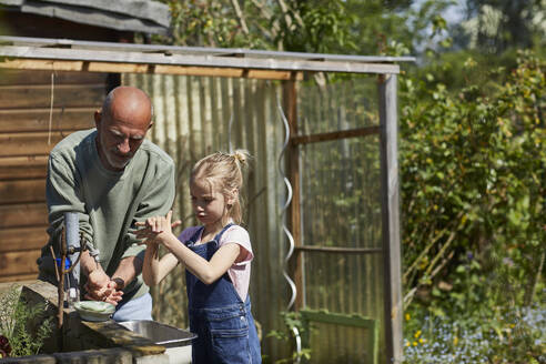 Großvater und Enkelin beim Händewaschen im Kleingarten - MCF00875