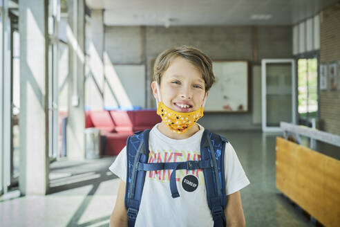 Porträt eines lächelnden Jungen mit Maske in der Schule - DIKF00504