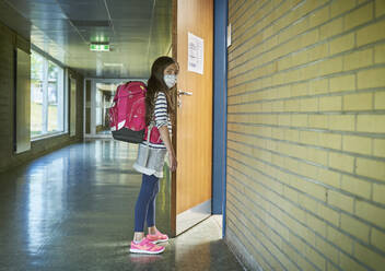 Girl wearing mask in school opening classroom door - DIKF00506