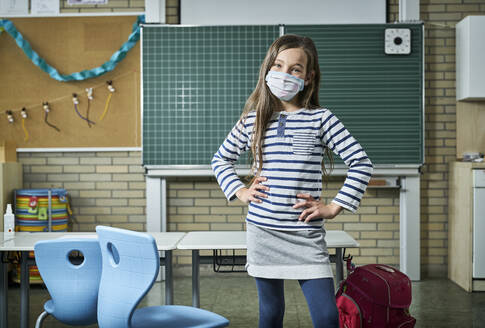 Portrait of confident girl wearing mask in classroom - DIKF00513