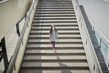 Mädchen mit Maske und Schultasche geht auf einer Treppe - DIKF00524