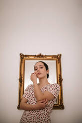 Young ballerina with classic mirror on wall in background at home - GRCF00250