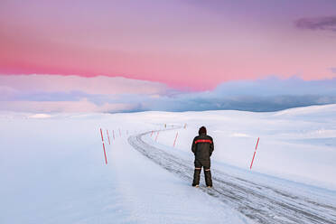 Mann steht auf der Straße in einer Winterlandschaft, Tana, Norwegen - WVF01584