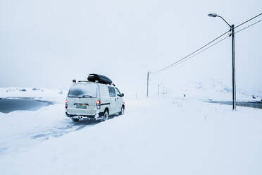Wohnmobil bei Schneesturm auf der Landstraße im Winter, Kongsfjord, Norwegen - WVF01590