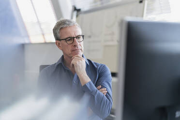 Nachdenklicher männlicher Unternehmer bei der Arbeit im Büro am Computer - DIGF11299