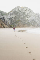 Frau hinterlässt Fußabdrücke beim Laufen am Strand von Ursa, Region Lisboa, Portugal - FVSF00374