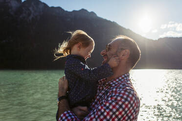 Vater trägt Tochter gegen Berg und See am Achensee, Bundesland Tirol, Österreich - JLOF00394