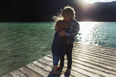 Brother kissing sister while standing on boardwalk at Achensee, Tyrol State, Austria - JLOF00400