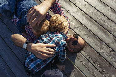 Shot of father lying with children on boardwalk at Achensee, Tyrol State, Austria - JLOF00404