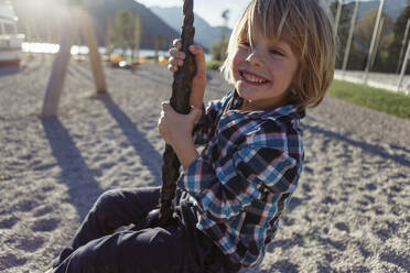 Happy boy swinging on rope at Achensee, Tyrol State, Austria - JLOF00410