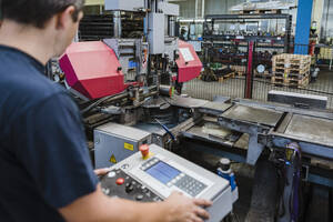 Ein Mann bedient eine Maschine in einer metallverarbeitenden Fabrik - DIGF11341