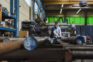 Mann arbeitet mit Metallstangen in einer Fabrik - DIGF11342