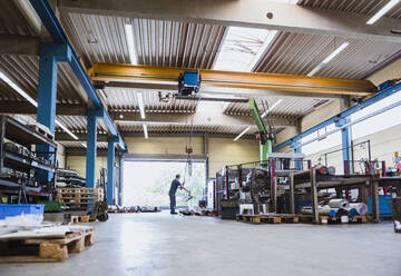 Man working with indoor crane in a factory - DIGF11350