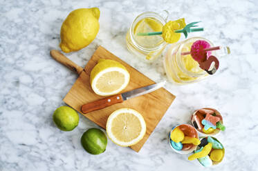 Schneidebrett, Küchenmesser, Zitronen, Limetten, Gummibonbons und Gläser mit frischer, selbstgemachter Limonade - KIJF03016