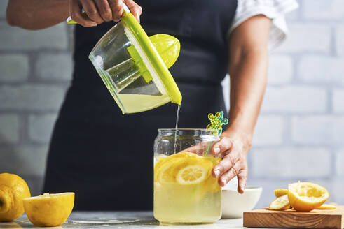 Hände einer Frau, die frische Limonade zubereitet - KIJF03027